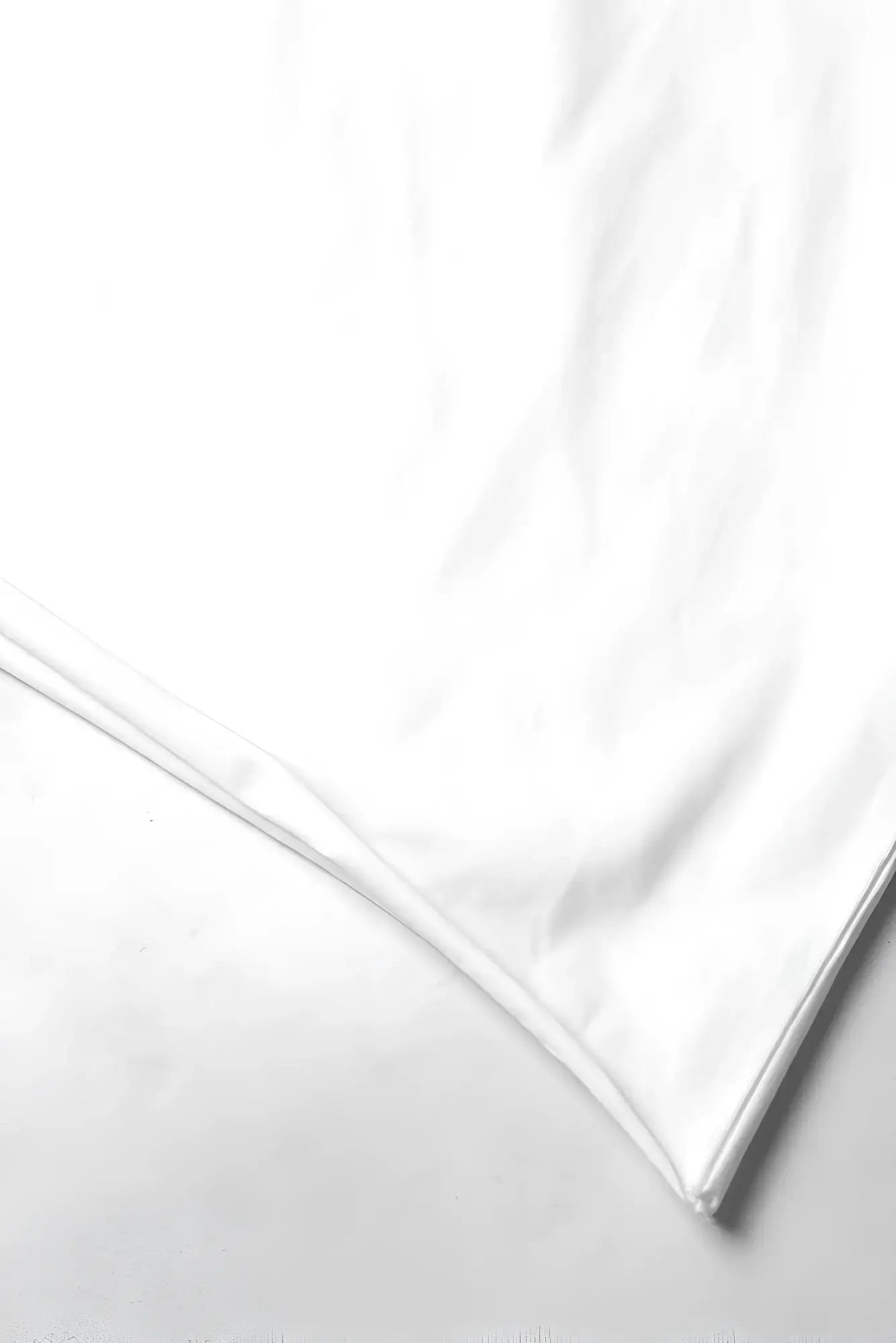 A crisp white silk pillowcase with smooth reflective surface and neatly finished edges displayed with an oversized raw-cut cropped tee white