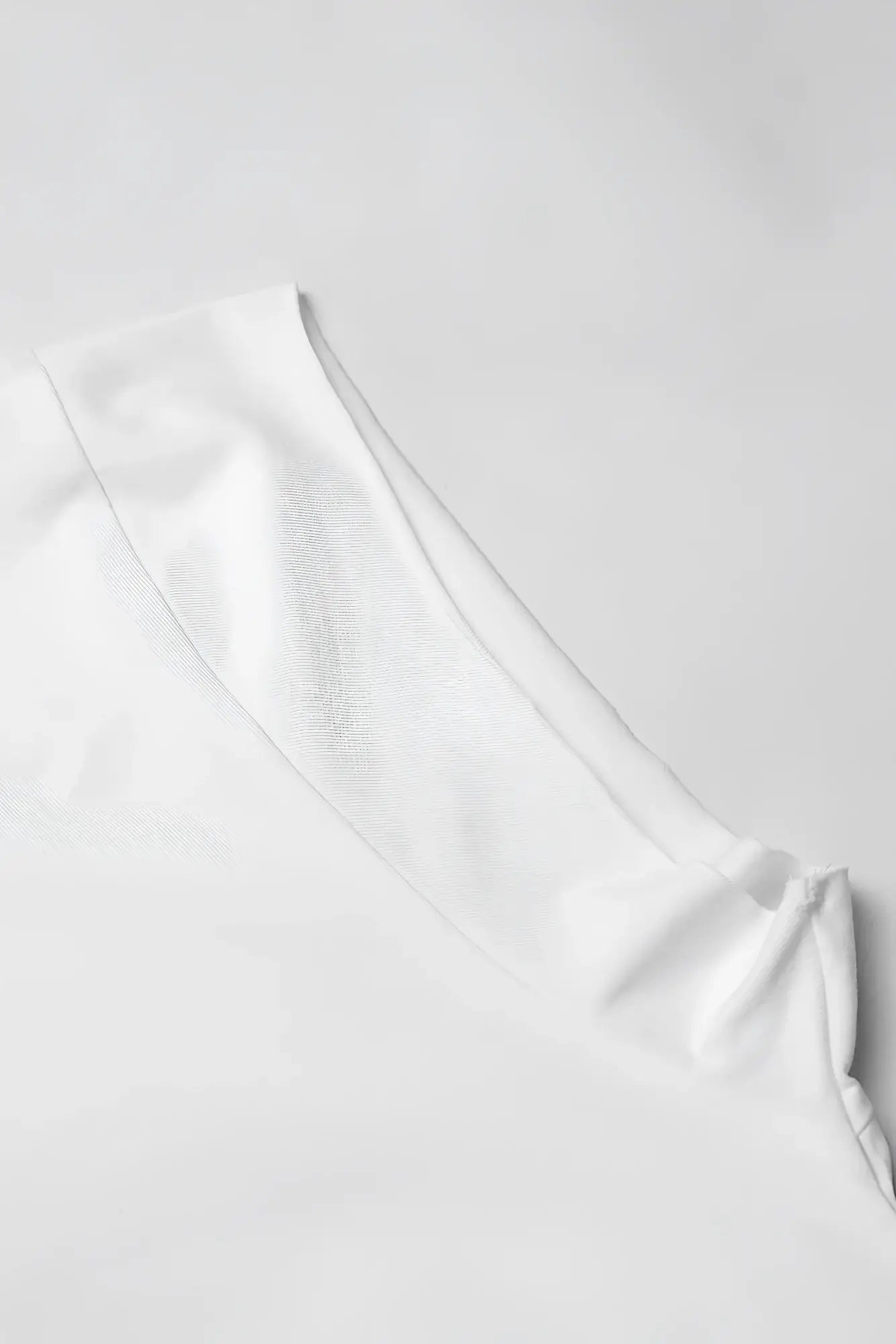 White oversized raw-cut cropped tee sleeve with smooth textured fabric and clean minimalist design