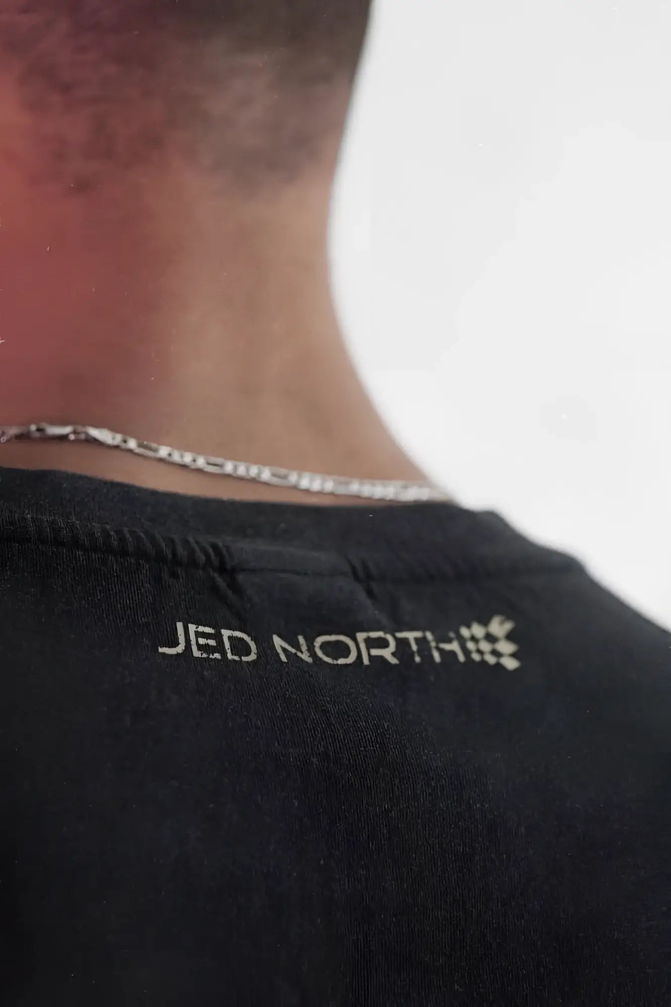 Back of black cotton Jed North oversized washed sleeveless t-shirt with white embroidered logo at neckline