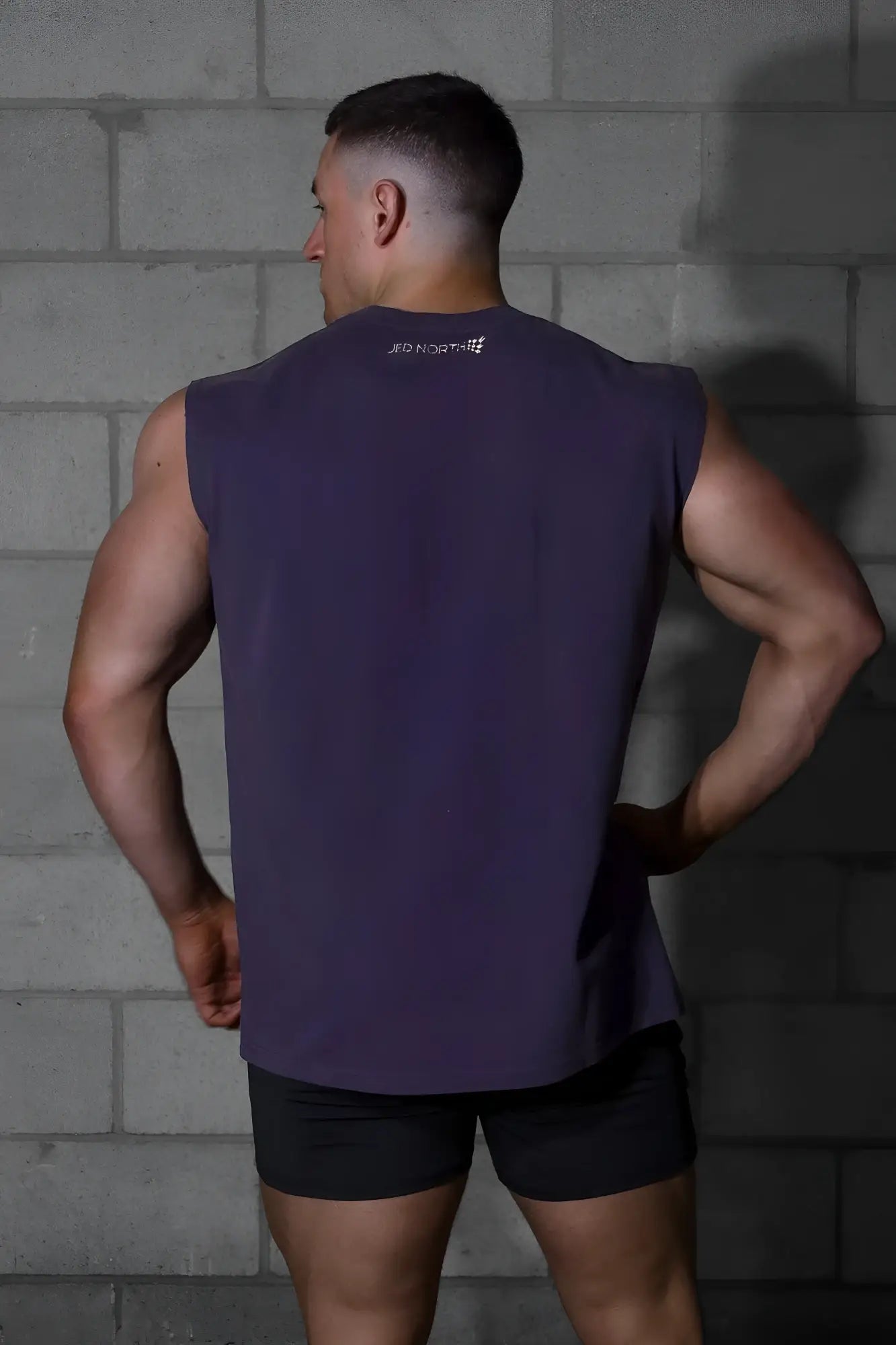 Dark purple sleeveless athletic tank top by jed north with a subtle white logo at the neckline for workouts