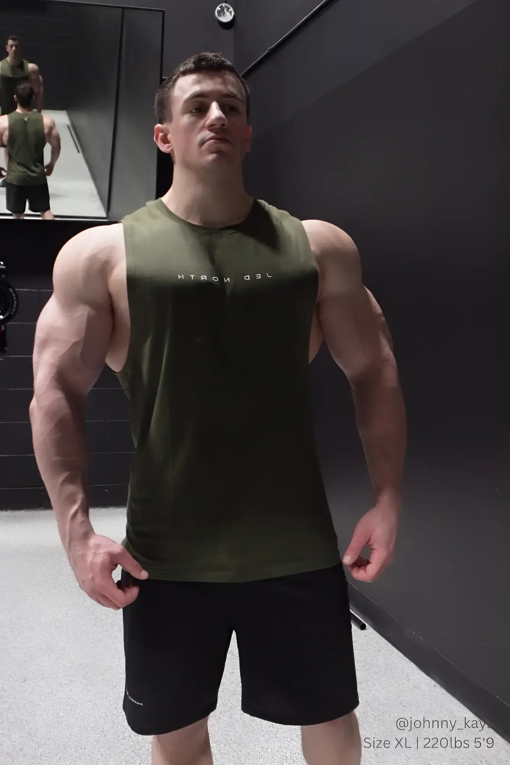 Olive green sleeveless athletic tank top with white lettering paired with black jed north performance air-tech shorts