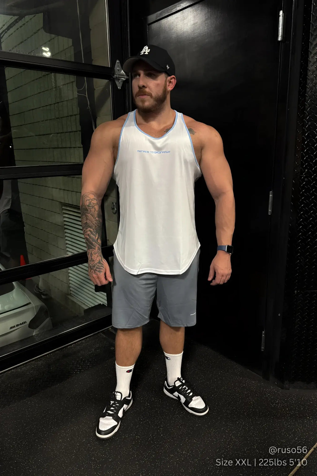 White tank top with light blue trim and subtle text across the chest paired with jed north gray performance air-tech athletic shorts