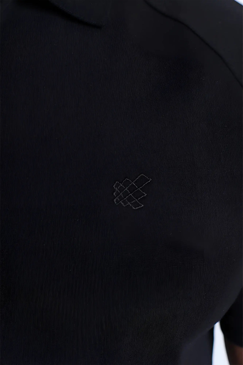 Premium muscle-fit black polo tee with textured fabric and subtle white geometric logo embroidered on the chest