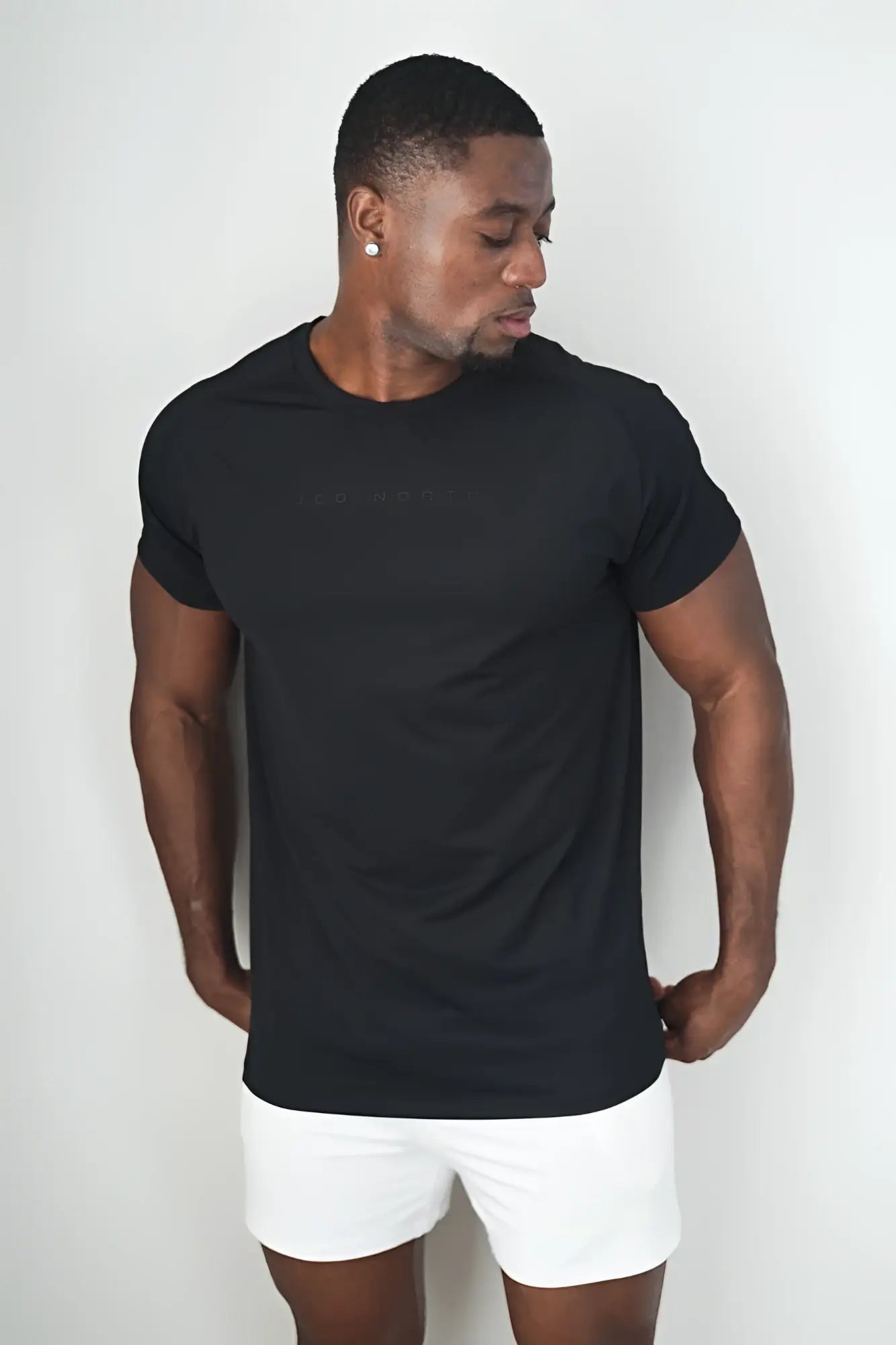 Black short-sleeved crew neck premium training tee with subtle embossed branding across the chest