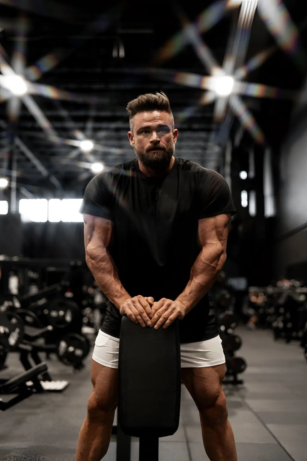 Black premium training tee with a sleek modern design displayed on a black weight bench for workout use
