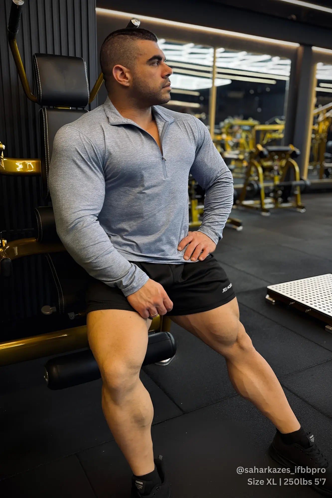 A man wearing a heather blue quarter-zip training long sleeve made of breathable fabric and black shorts with white branding