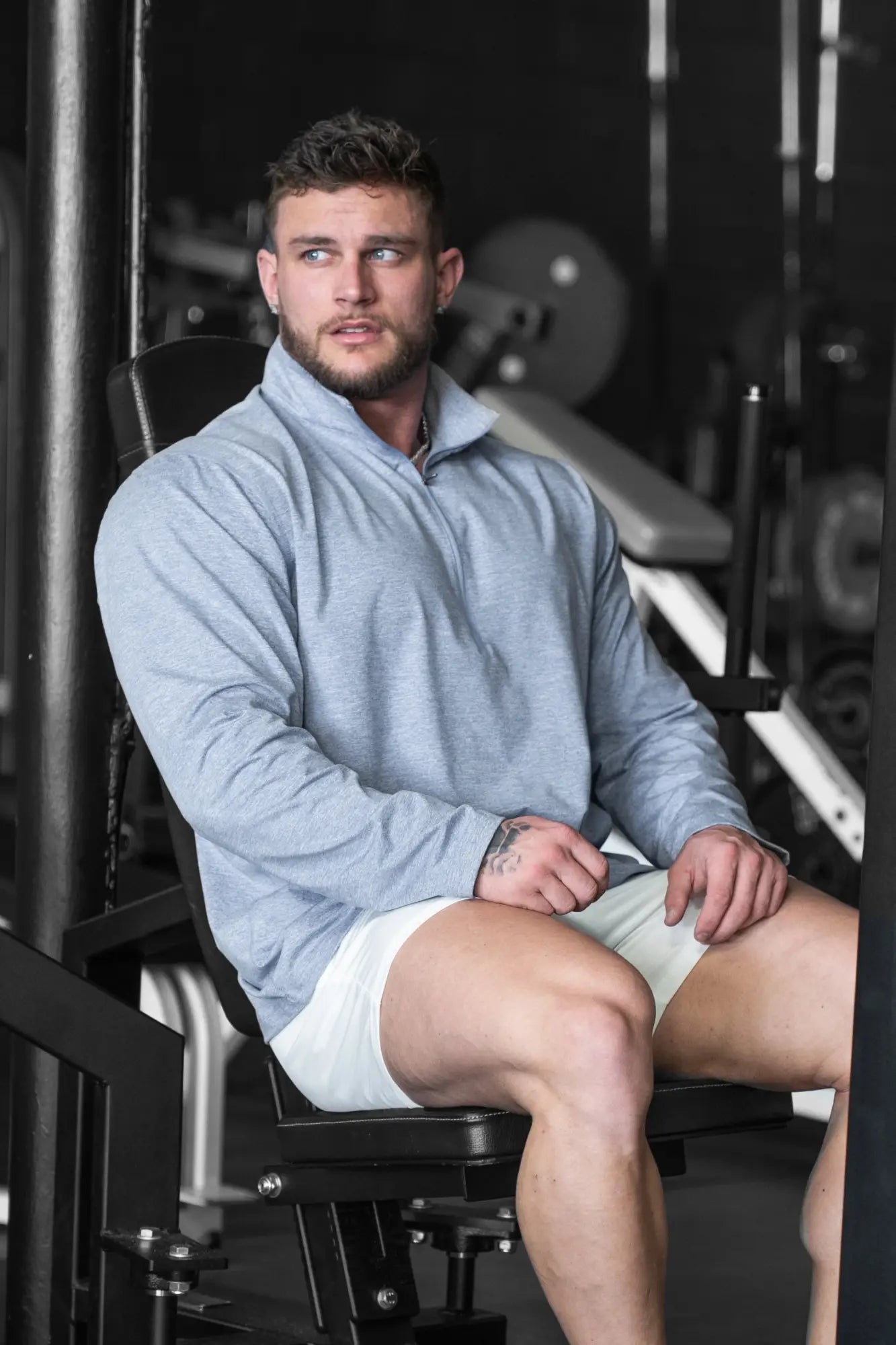 A man wearing a heather blue quarter-zip training long sleeve pullover with a half-zip collar and white shorts