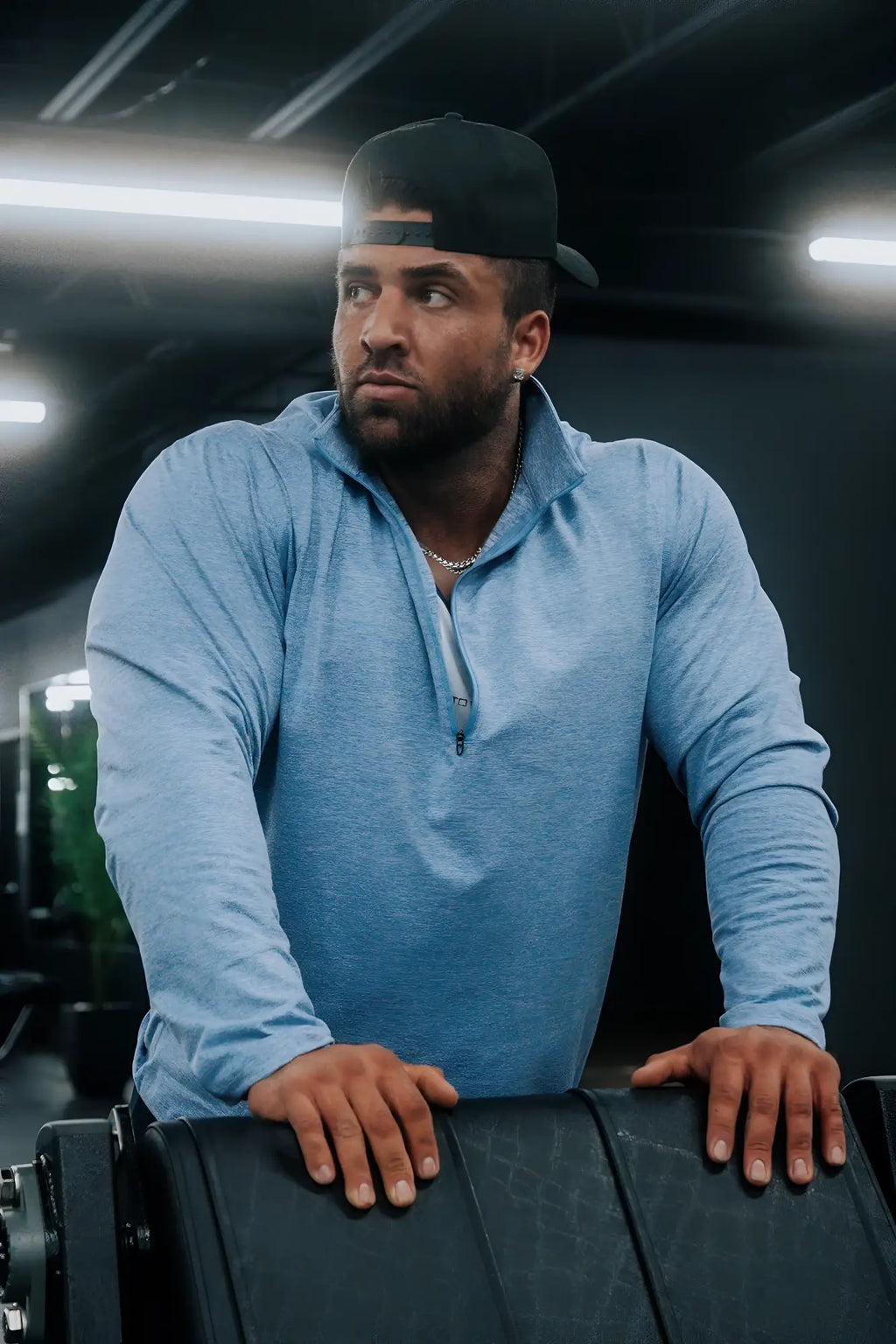 A man wearing a heather blue quarter-zip training long sleeve with a subtle heathered texture
