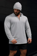 A man wearing a heather gray quarter-zip training long sleeve shirt with ribbed cuffs and collar