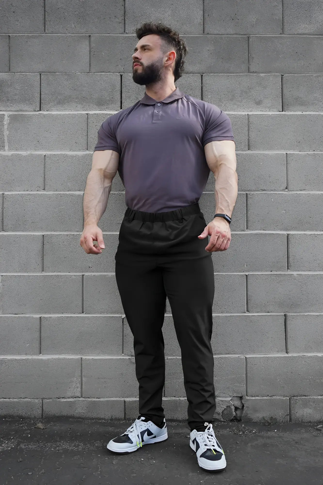 A man wearing a fitted purple polo shirt with black jed north quick-dry tech pants designed for athletic use