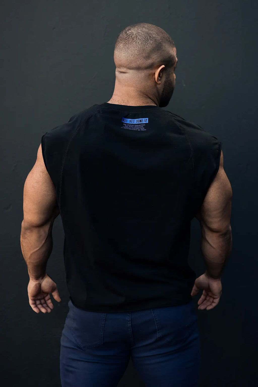 Black sleeveless raglan muscle tank top with a small blue label at the neckline for athletic wear