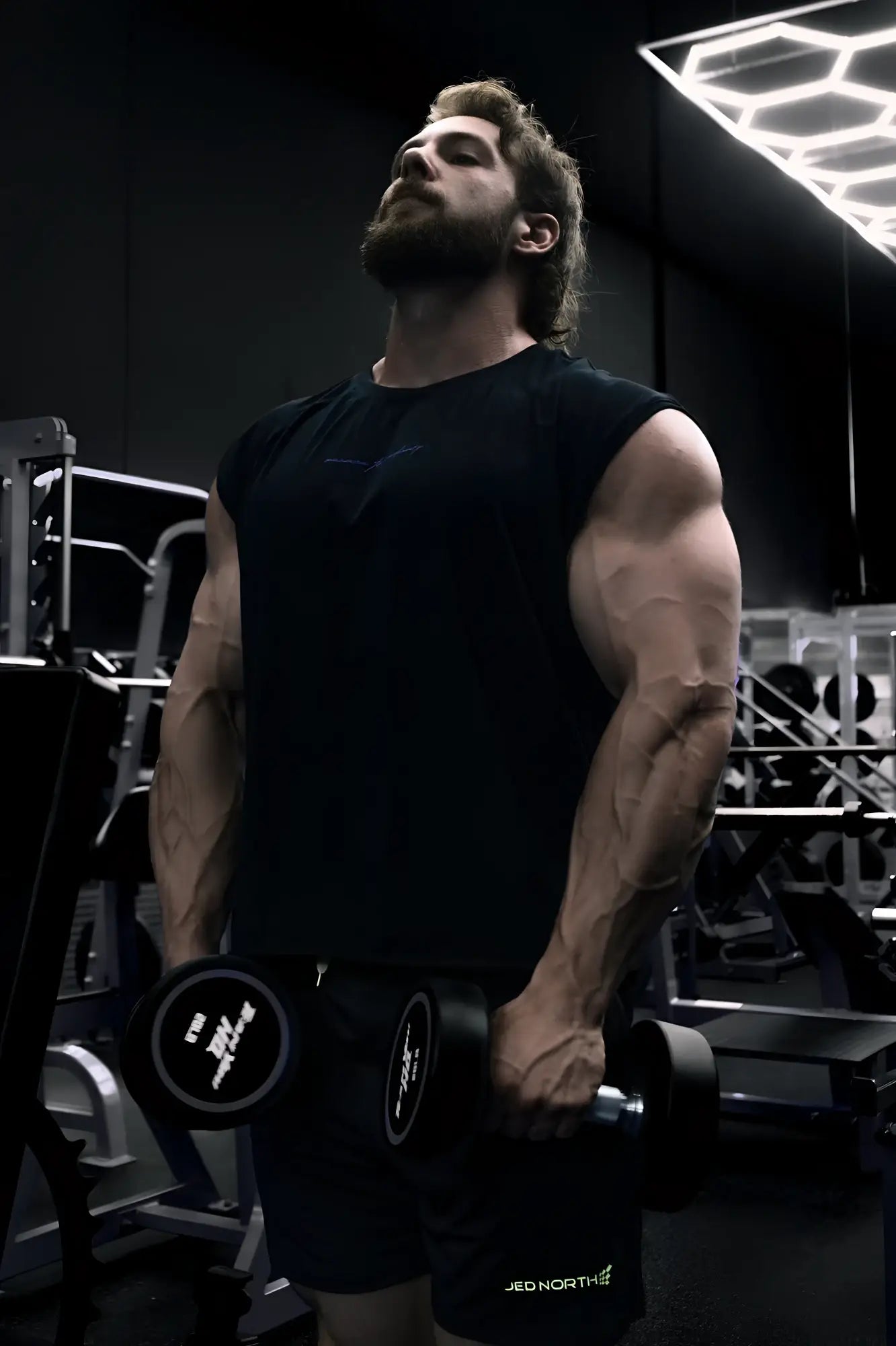 Black dumbbell with matte finish and white branding on the weight plates shown with raglan sleeveless muscle tank all black