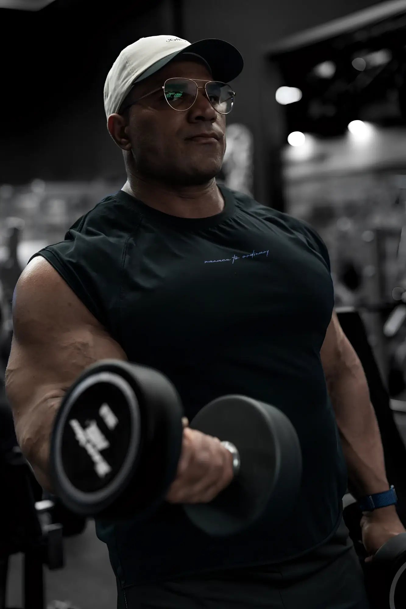 Black dumbbell with white logo on weight plate shown with raglan sleeveless muscle tank all black for gym use