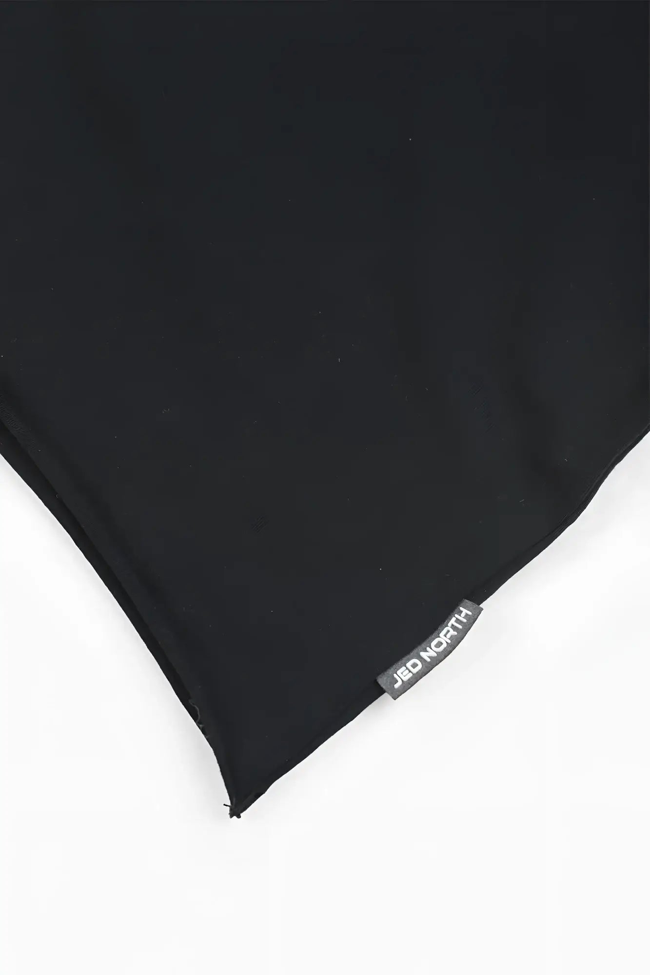 Black fabric scarf with subtle sheen and small gray jad north brand tag paired with raglan sleeveless muscle tank