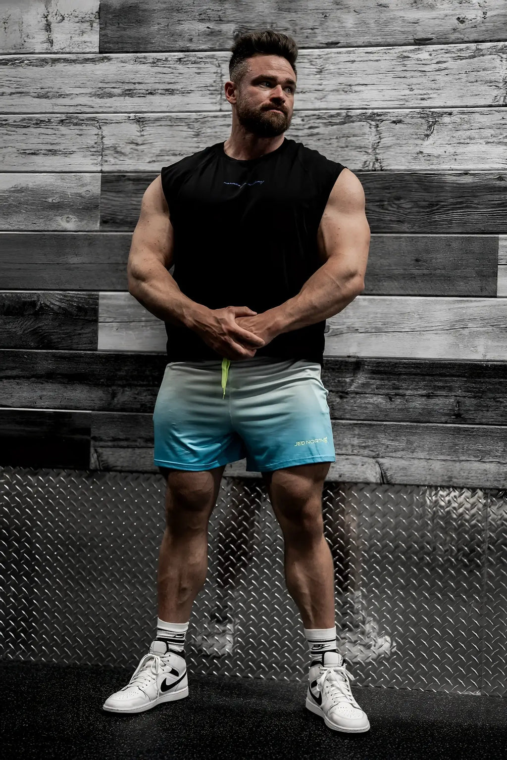 Men’s gradient blue to white athletic shorts with neon green drawstring and subtle logo paired with raglan muscle tank