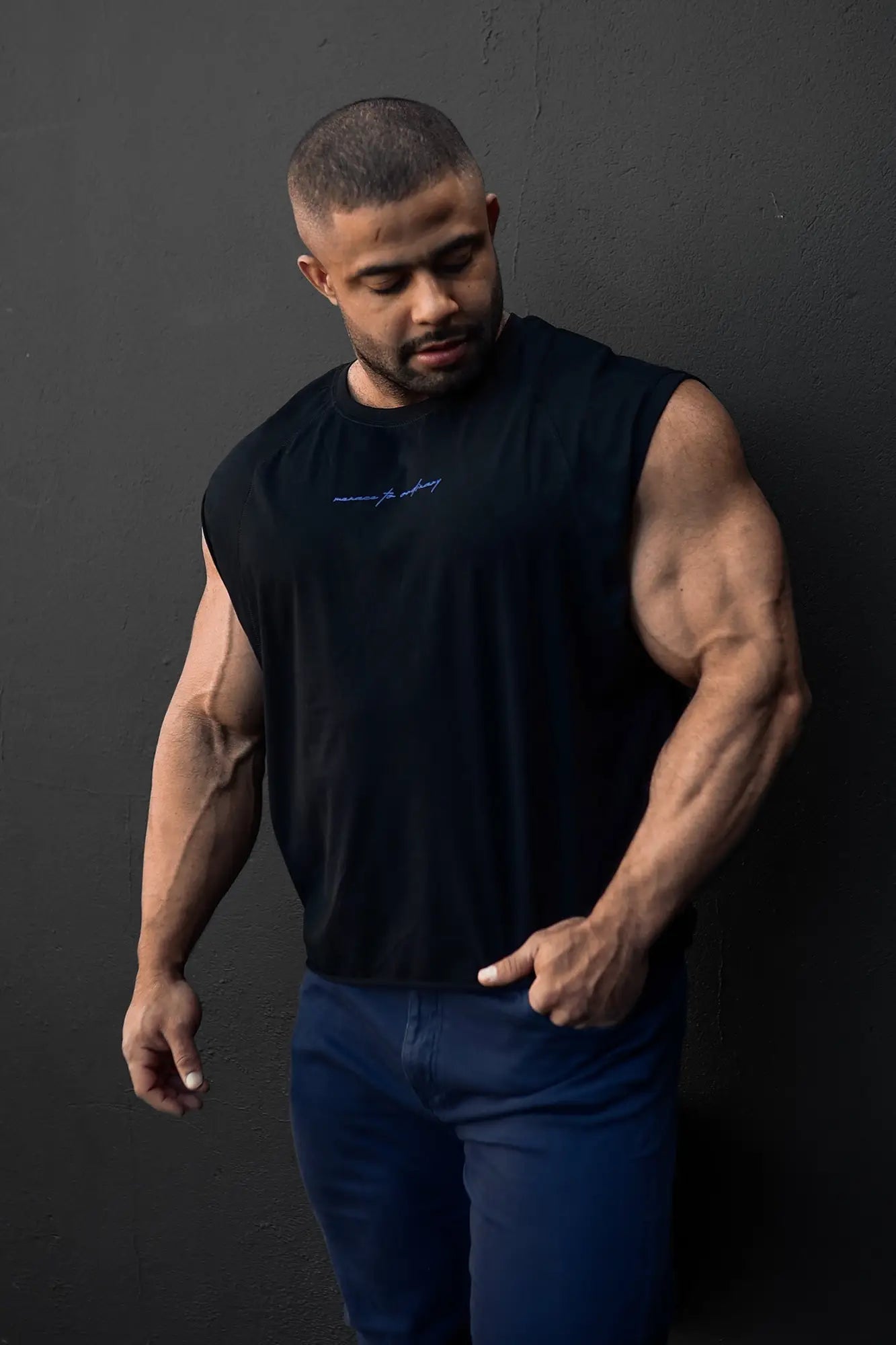 Black sleeveless raglan muscle tank with subtle embroidered logo on chest perfect for workouts and casual wear