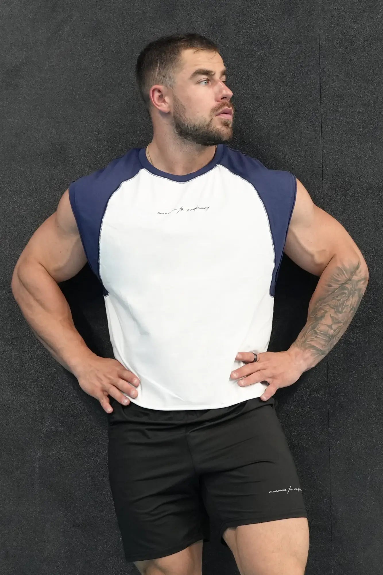 A man wearing a white and navy blue raglan sleeveless muscle tank designed for athletic use
