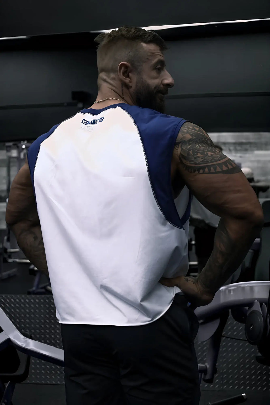 Back view of a white and navy raglan sleeveless muscle tank with a small logo on the back collar