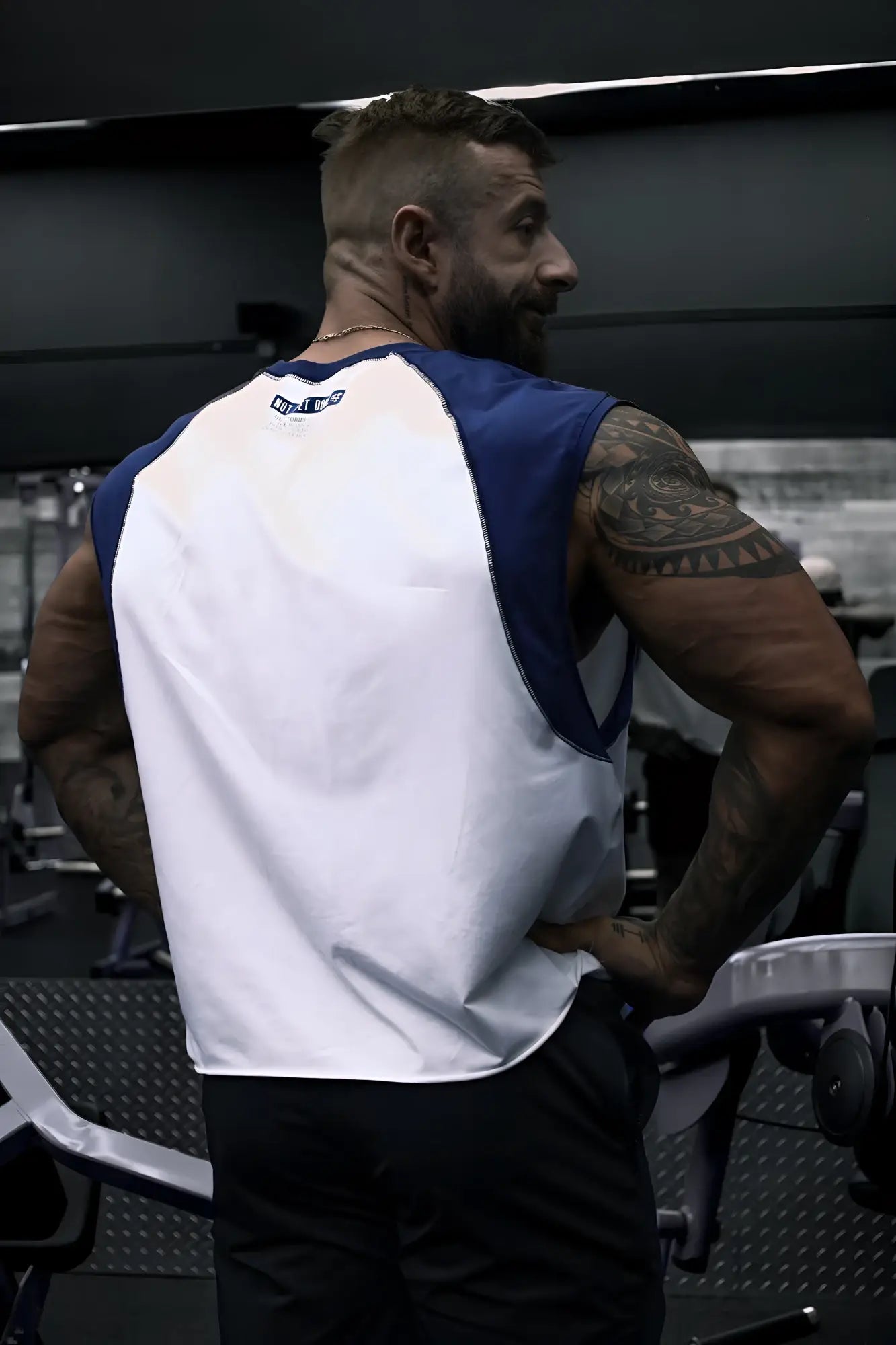 Back view of a white and navy raglan sleeveless muscle tank with a small logo on the back collar