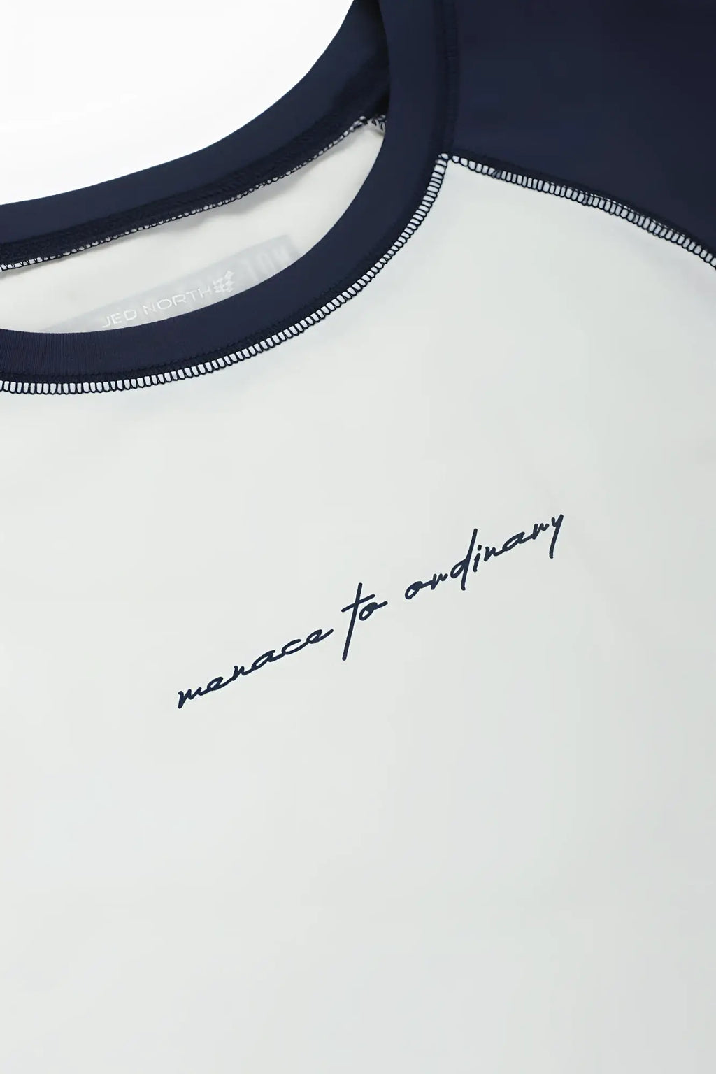 White and navy blue raglan sleeveless muscle tank with black cursive embroidery manace to ordinary on chest