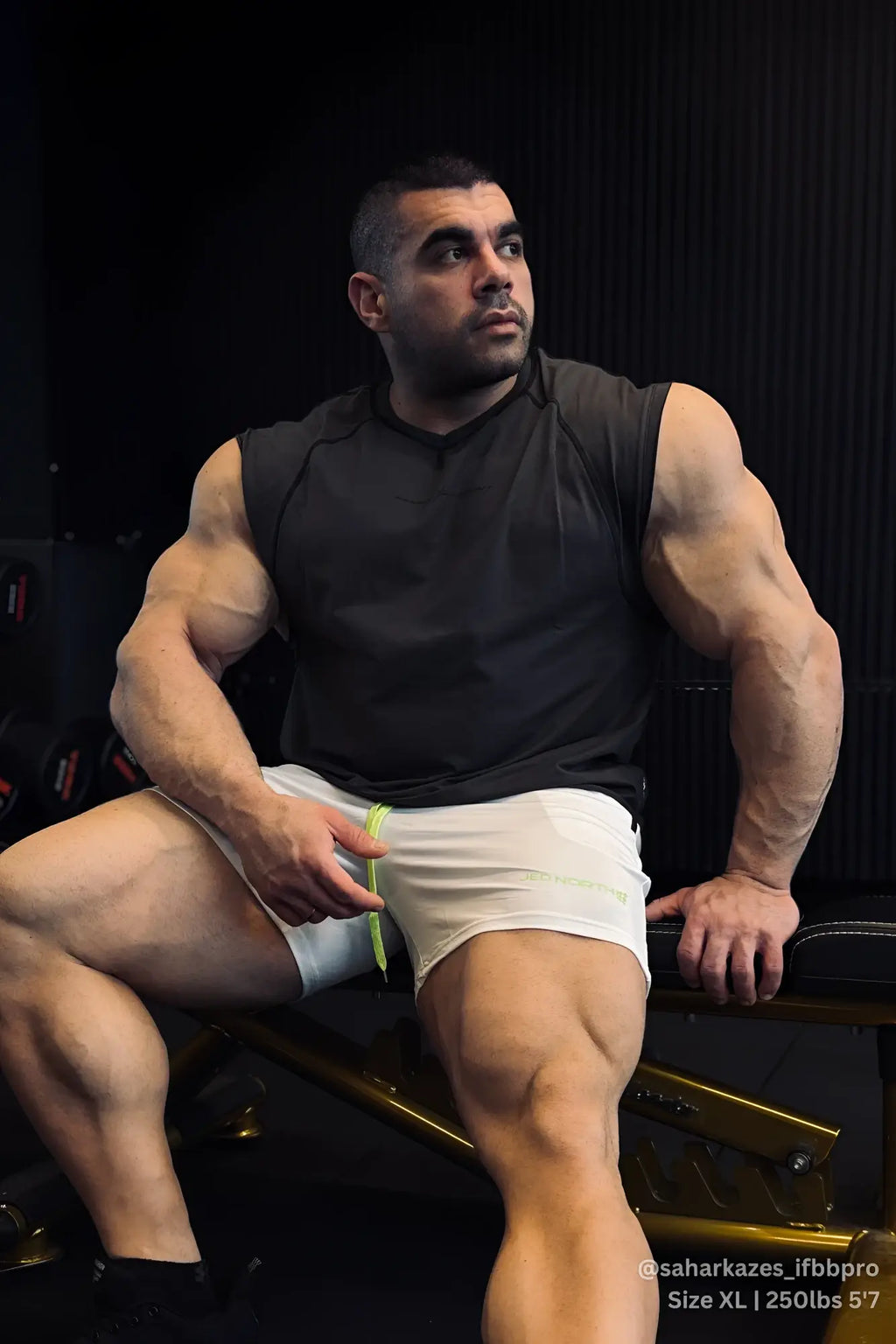 A man wearing a dark gray raglan sleeveless tank top with a black sleeveless athletic top and white shorts