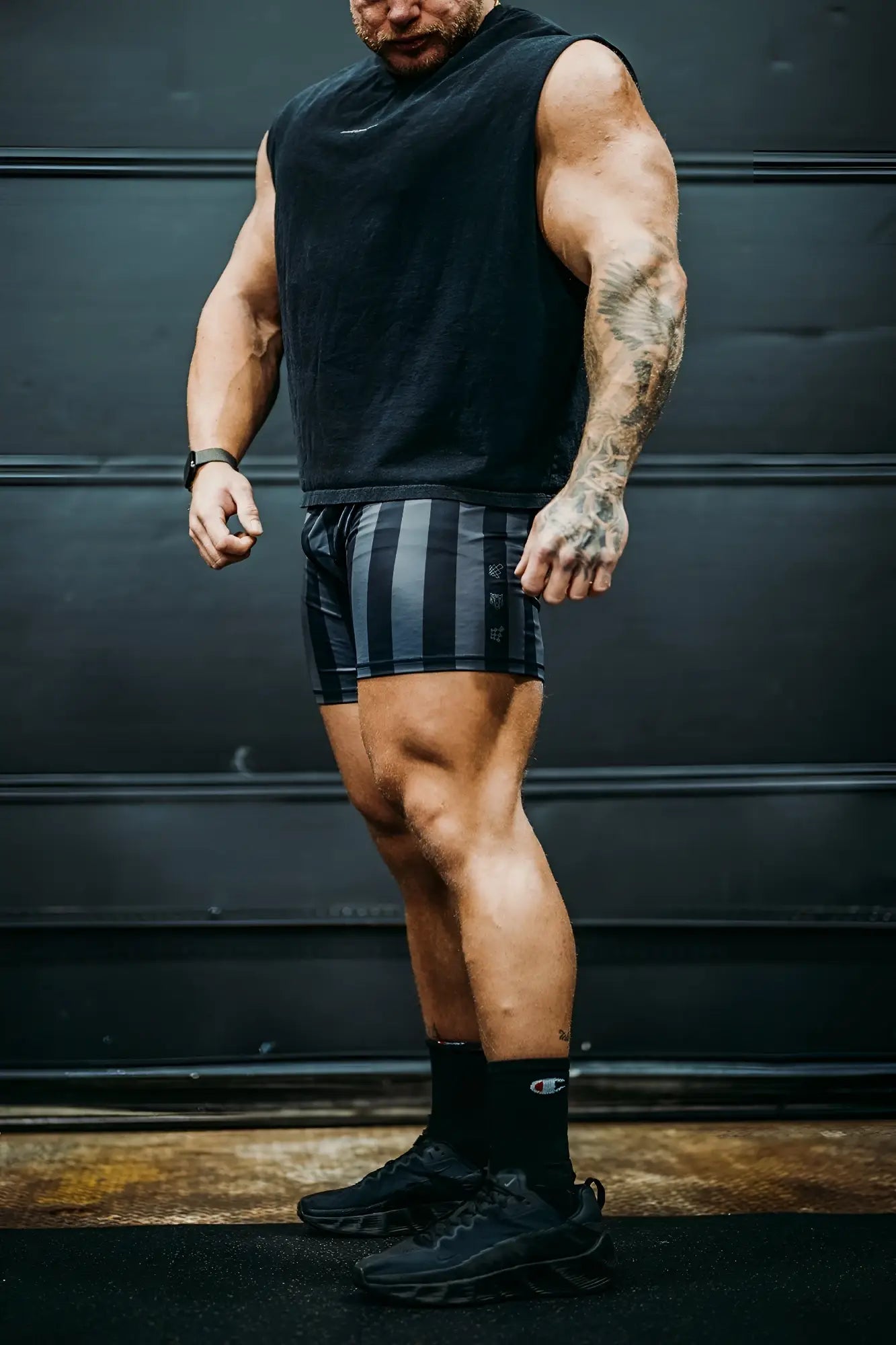 Black sleeveless athletic top with subtle white logo on chest paired with retro bodybuilding shorts black and gray