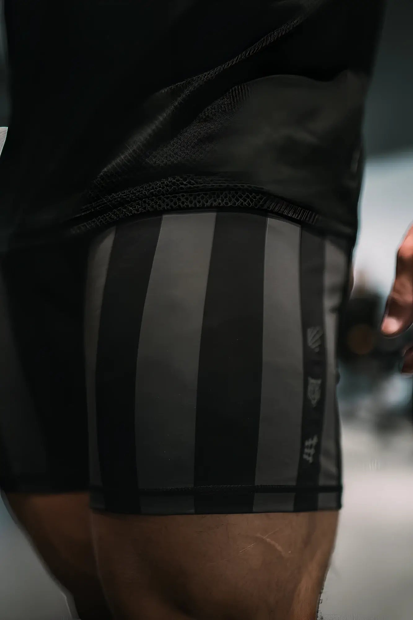 Retro bodybuilding shorts in black and gray with vertical stripes and subtle side logo for athletic use