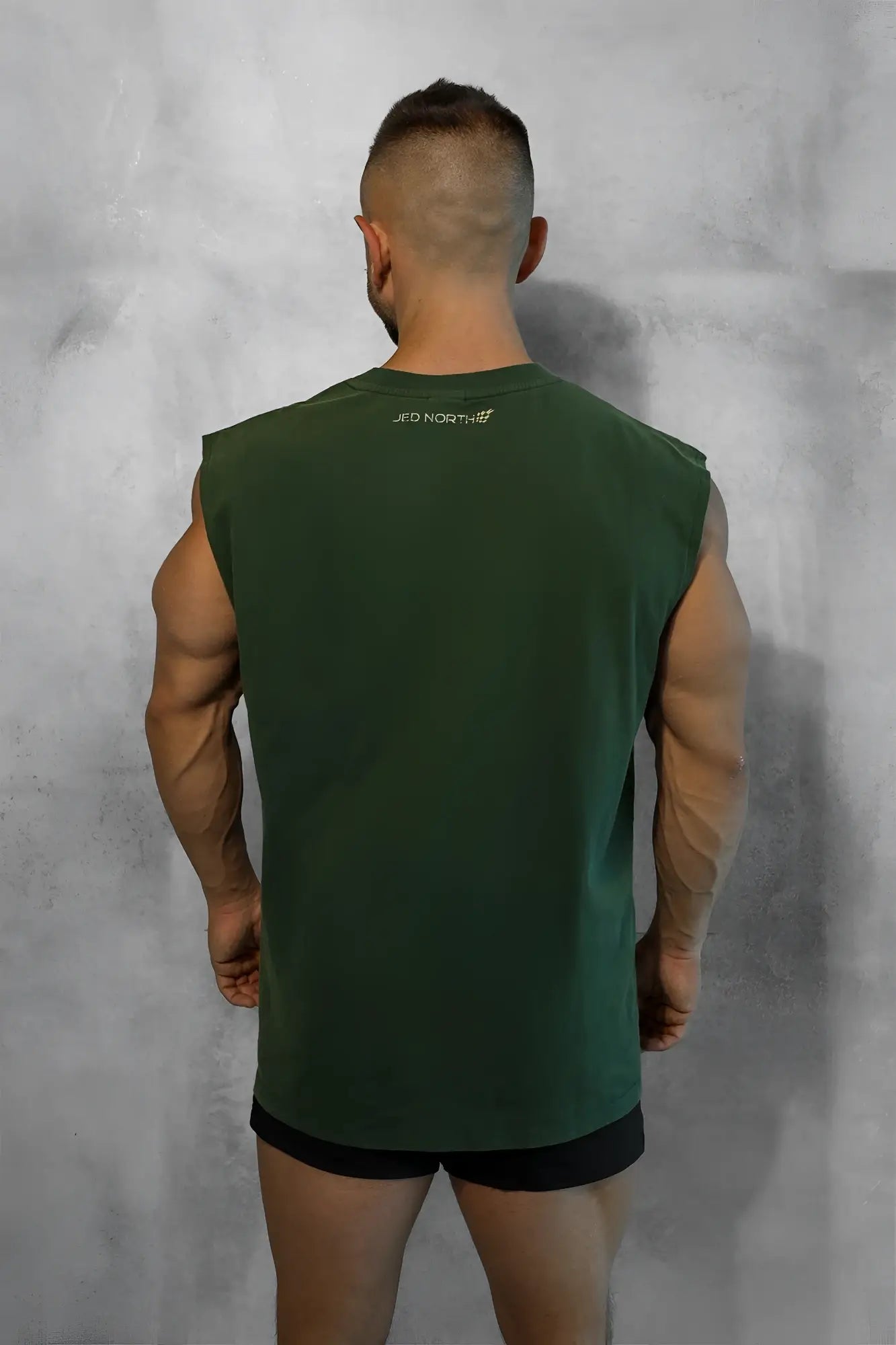 Dark green sleeveless muscle tank top with a small white logo on the upper back shown from the back side
