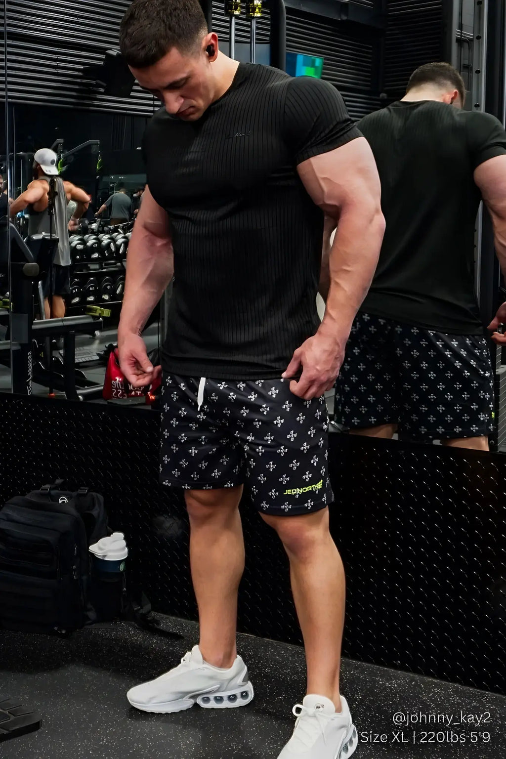 Black athletic shorts with subtle white cross pattern and small green logo on lower right leg by jed north
