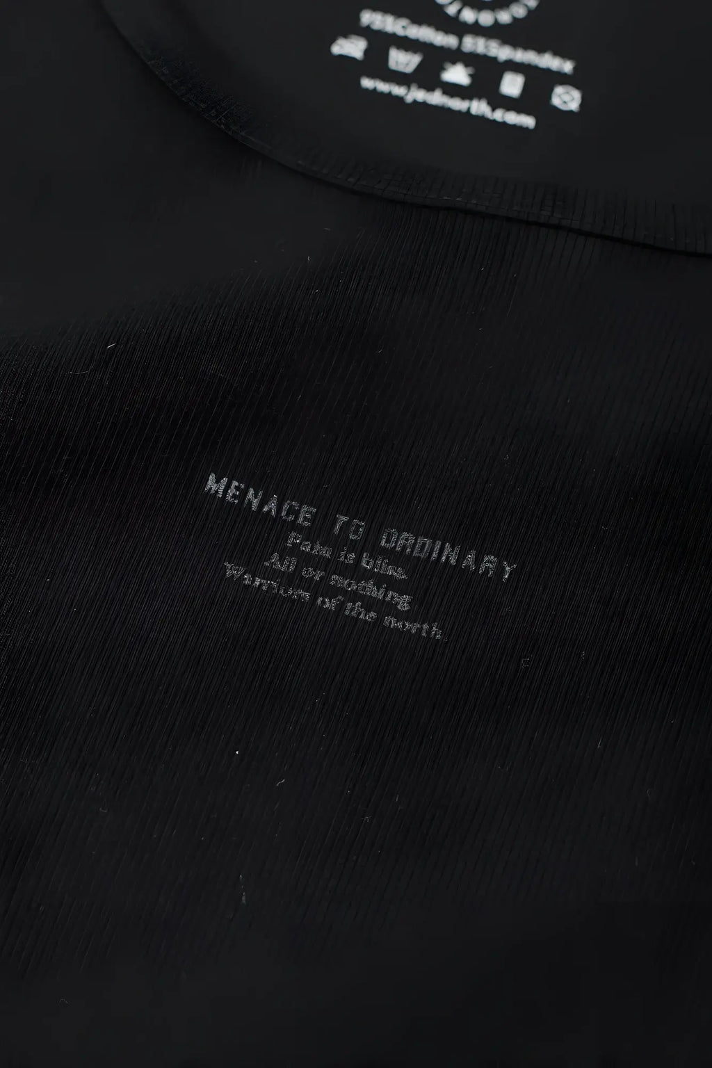 Black ribbed muscle tank top with white menace to ordinary text and care instructions inside collar