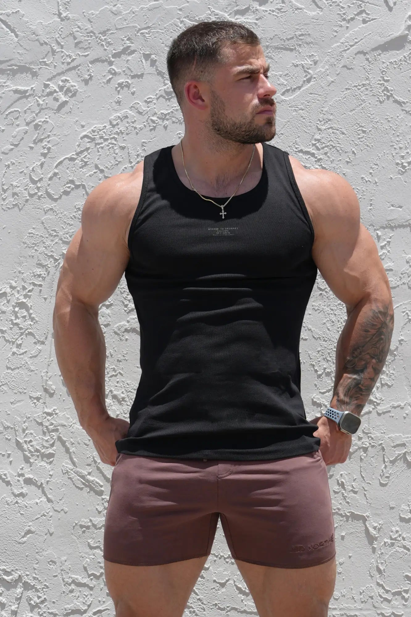 Black ribbed muscle tank top sleeveless with subtle chest logo and thin silver chain necklace
