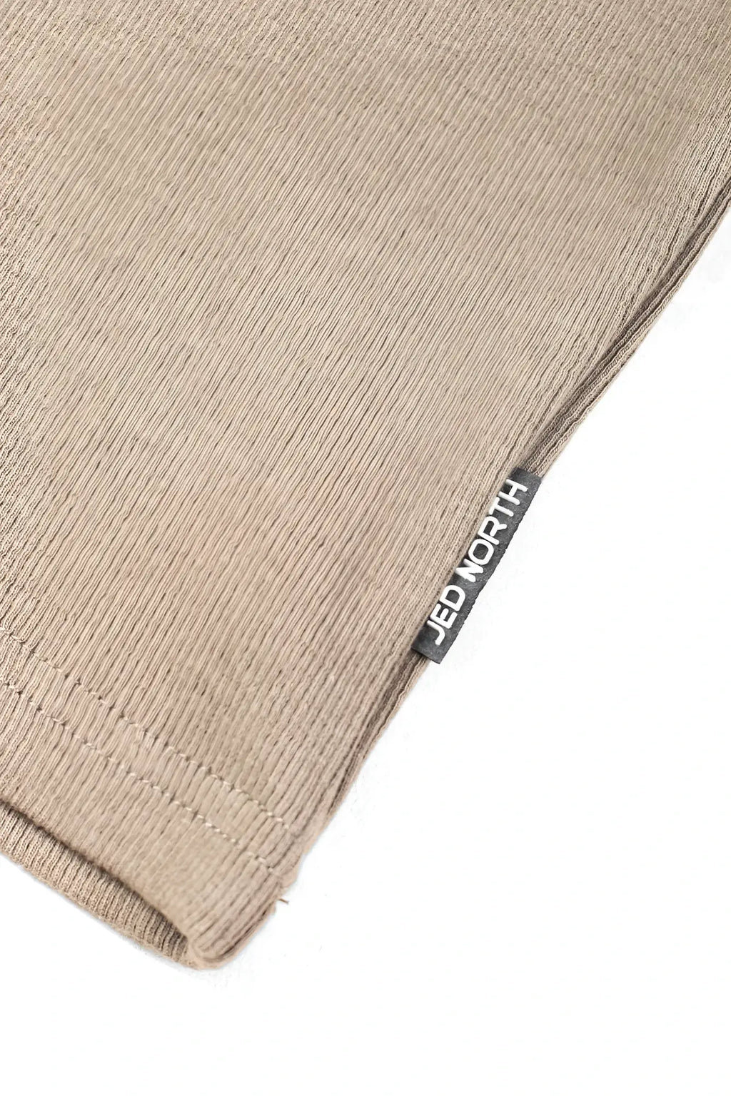 Beige ribbed knit fabric with black jed north tag on khaki ribbed muscle tank top