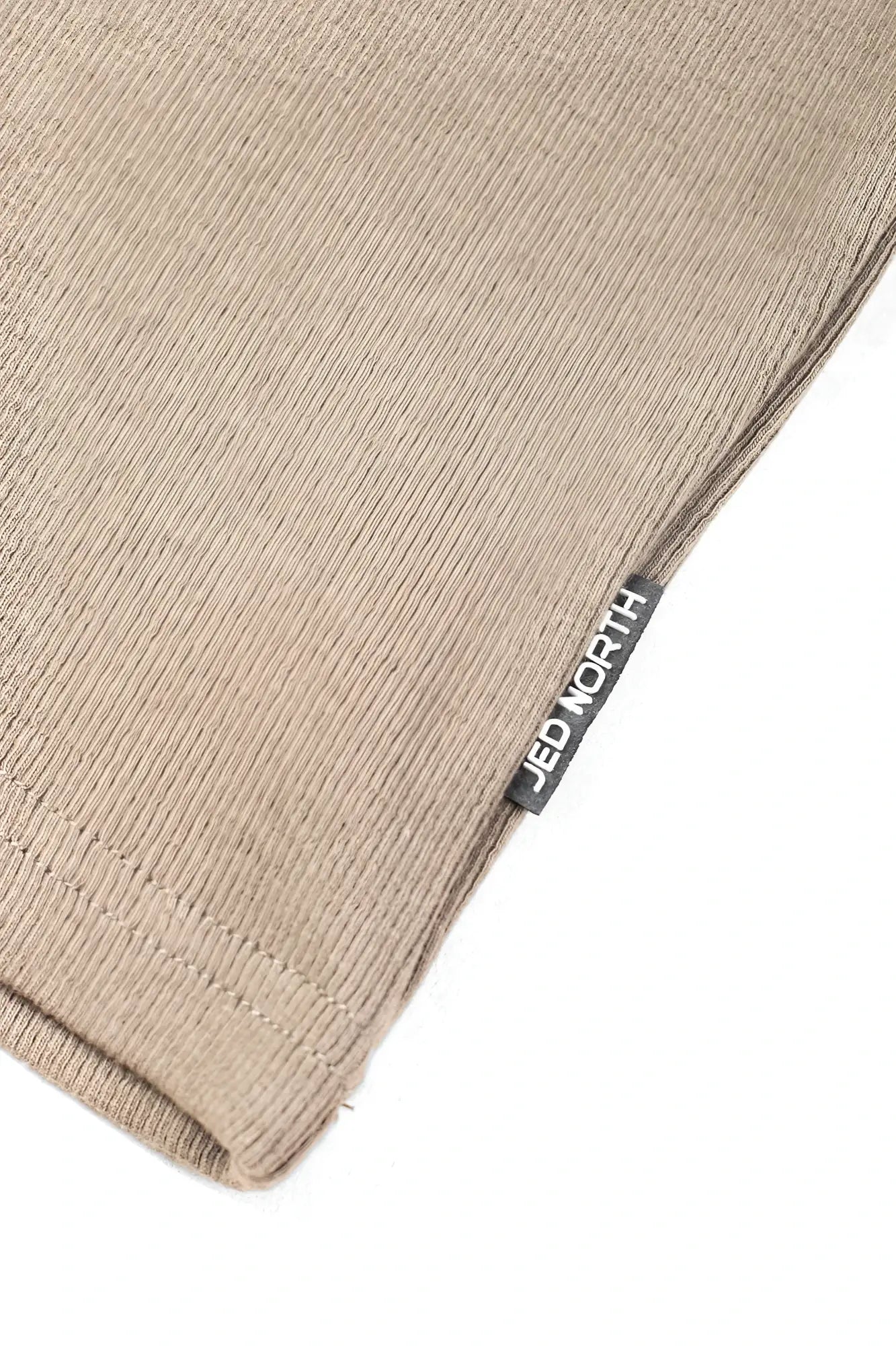 Beige ribbed knit fabric with black jed north tag on khaki ribbed muscle tank top