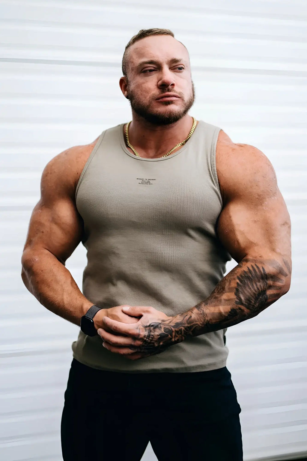 A man wearing a khaki ribbed muscle tank top with a small logo on the chest in beige sleeveless design