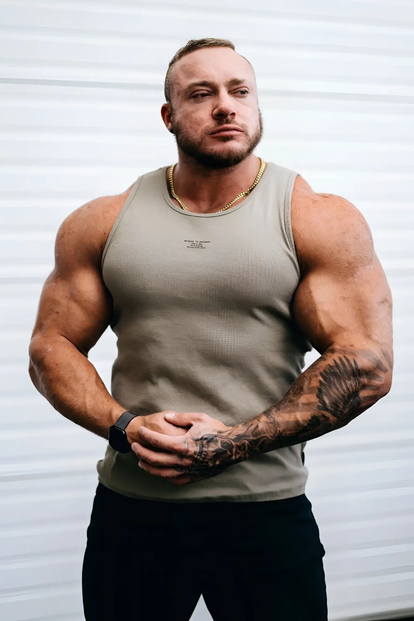 A man wearing a khaki ribbed muscle tank top with a small logo on the chest in beige sleeveless design
