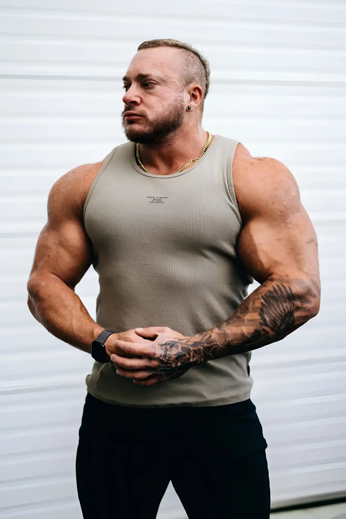 A muscular man wearing a khaki ribbed muscle tank top made of soft fabric with subtle chest text
