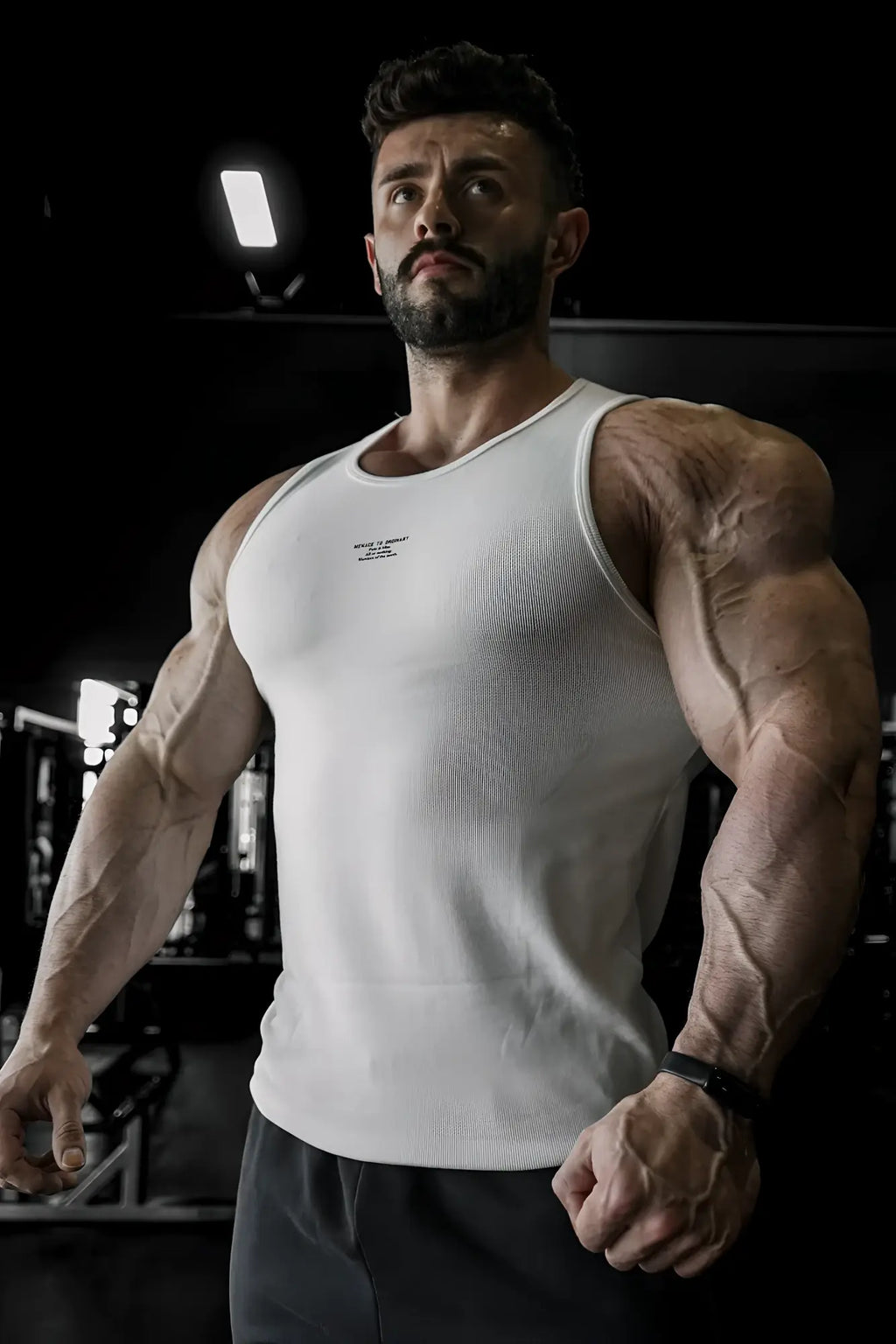 White ribbed muscle tank top with a small black logo on the chest made of stretchy cotton blend fabric
