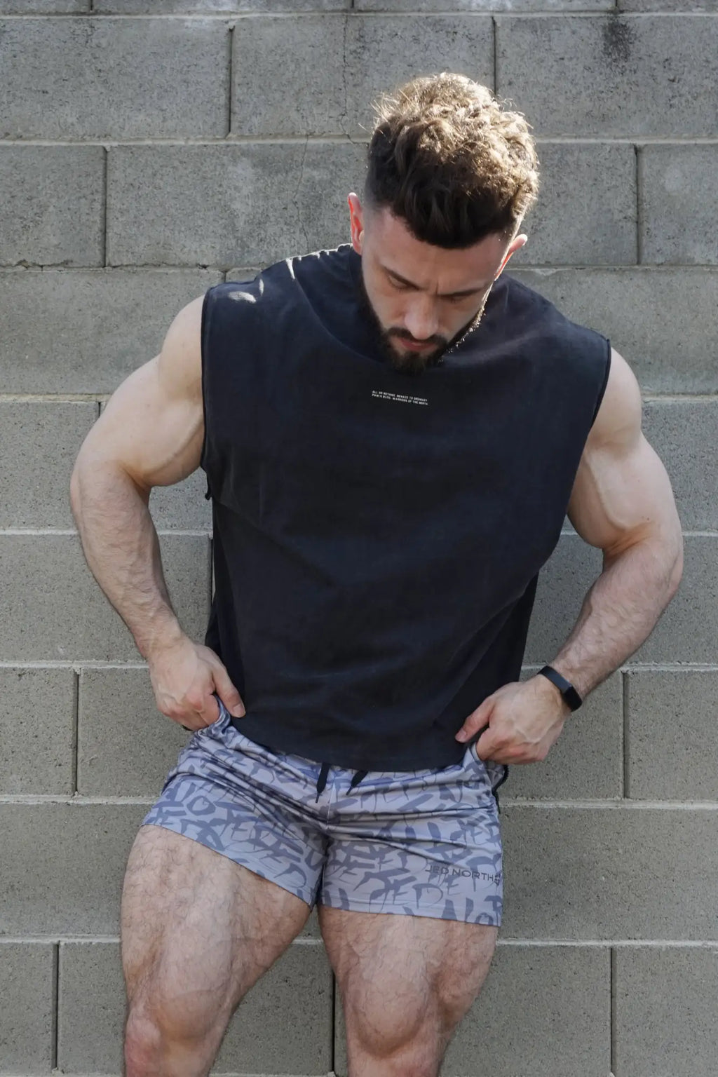 Black sleeveless athletic top jed north sleeveless box cut tank top with subtle chest logo for workout use