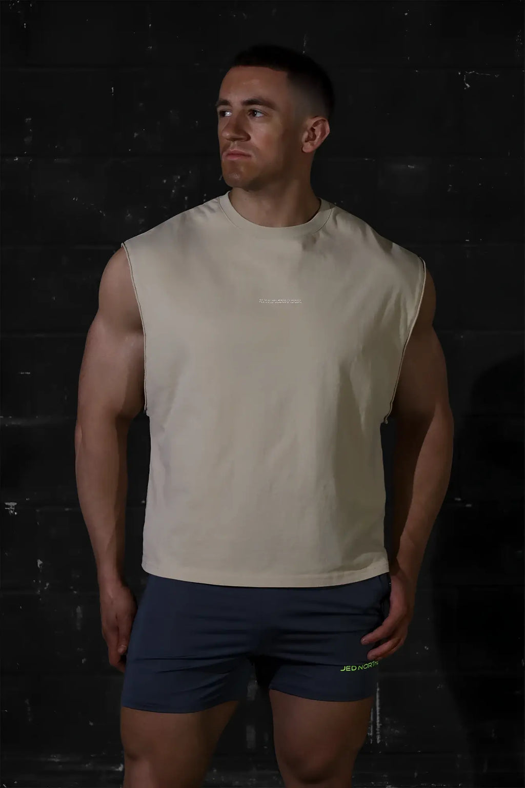 Beige sleeveless athletic tank top by jed north with subtle chest logo in light khaki for workout and casual wear