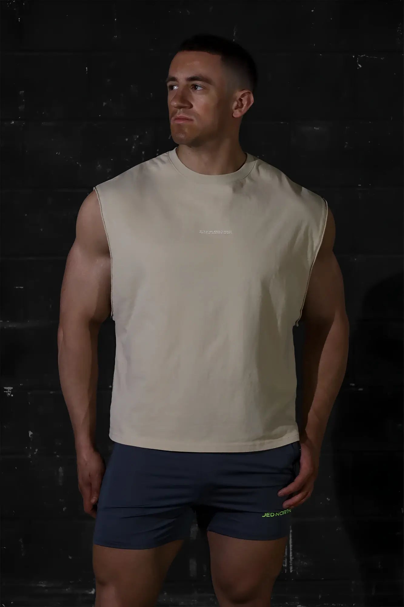 Beige sleeveless athletic tank top by jed north with subtle chest logo in light khaki for workout and casual wear