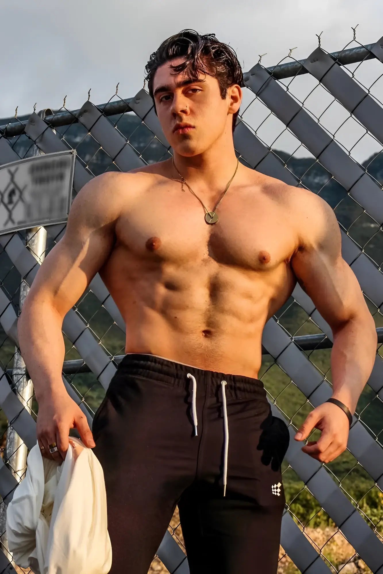 A muscular man stands shirtless wearing black spirit joggers with white drawstrings and a logo on the left leg