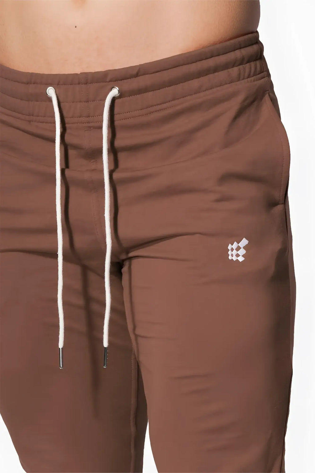 Jed North Spirit joggers are brown athletic pants featuring white drawstrings and a small white geometric logo on the thigh