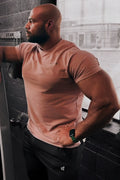 A muscular man wearing a jed north titan 2.0 muscle-fit soft peach athletic t-shirt with a chest logo
