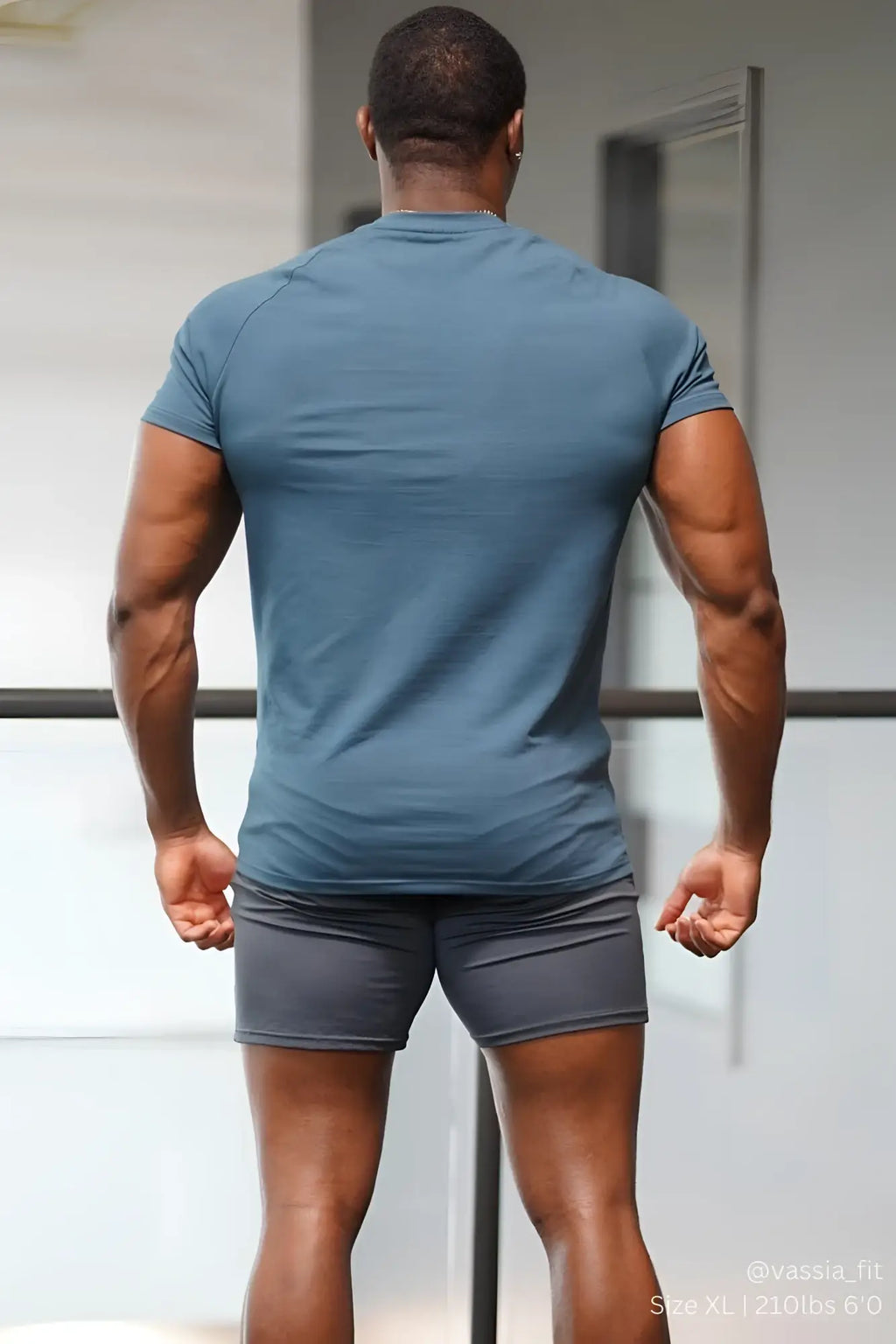 A man wearing a jed north titan 2.0 muscle-fit dark teal short-sleeved athletic t-shirt and gray shorts