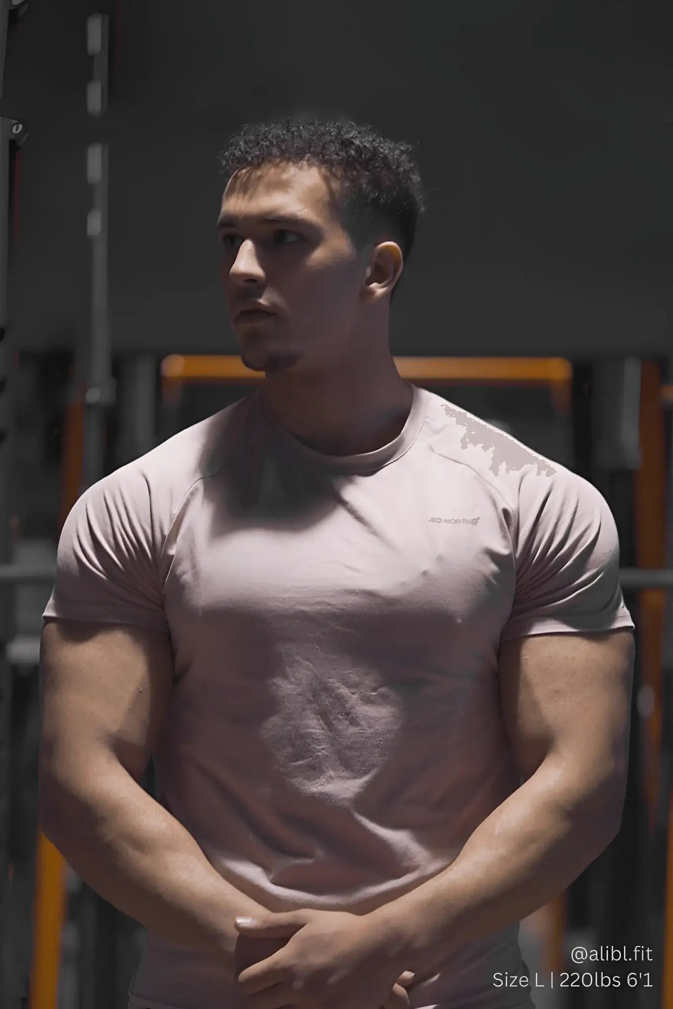 A man wearing a salmon jed north titan 2.0 muscle-fit t-shirt with subtle chest branding in light pink material