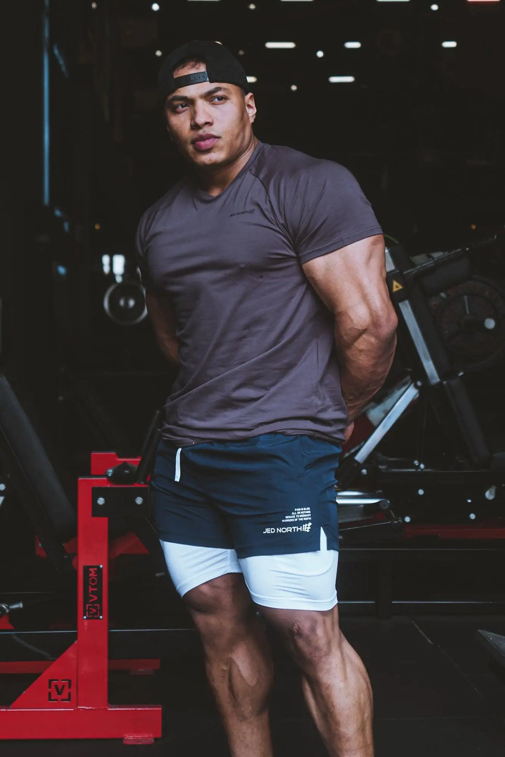 Dark navy blue athletic shorts with white inner layer and jed north branding on left leg paired with taupe muscle-fit t-shirt