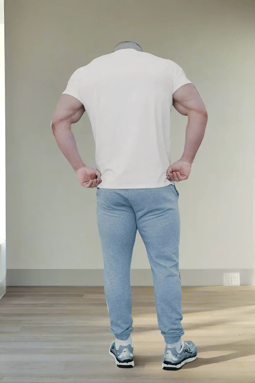 A man wearing a jed north titan 2.0 muscle-fit white short-sleeved t-shirt with light blue jogger pants