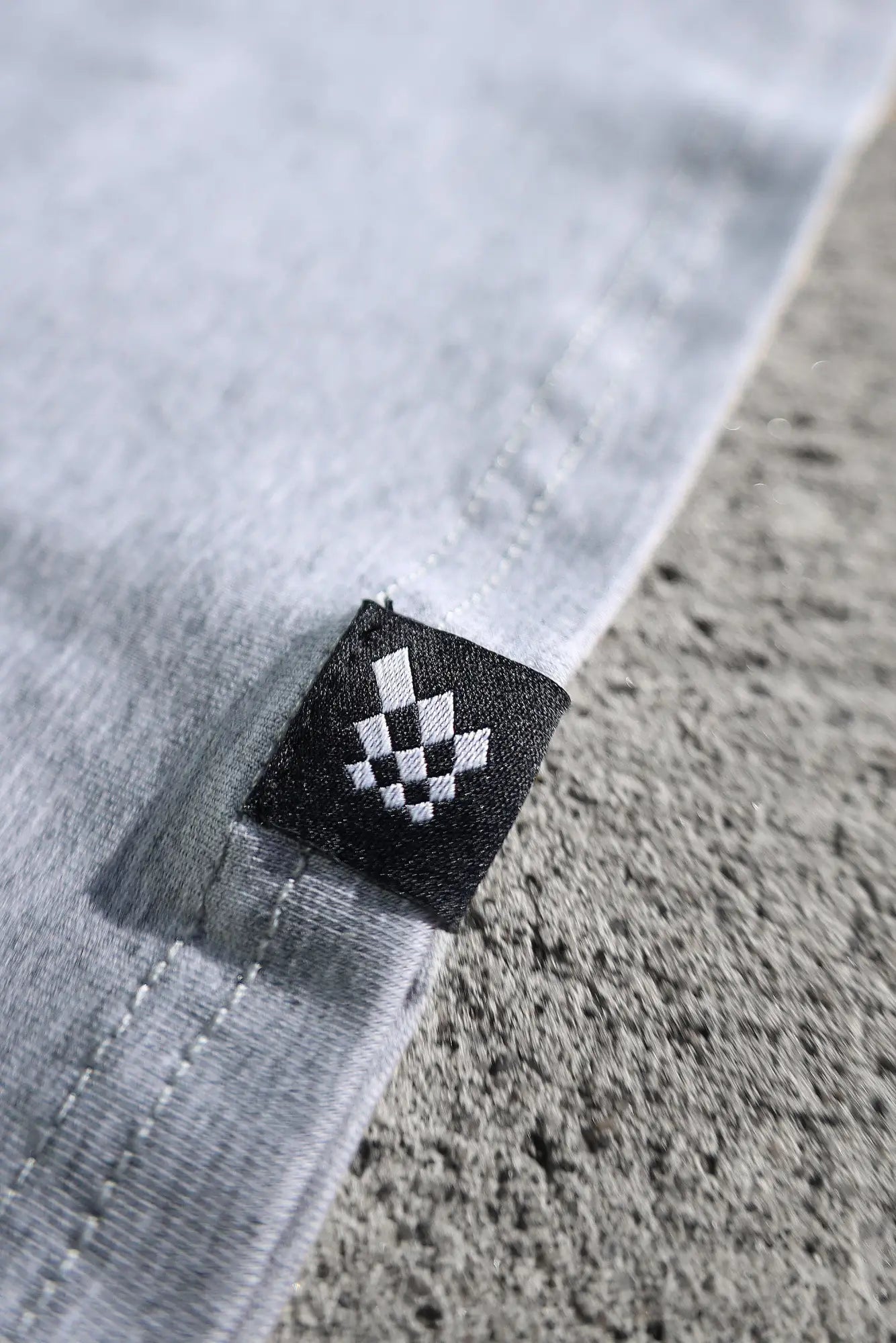 Black woven label with white checkered diamond pattern stitched on the hem of jed north titan muscle-fit platinum