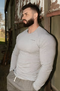 A man wearing a jed north titan muscle-fit long sleeve shirt in heather gray with a small chest logo