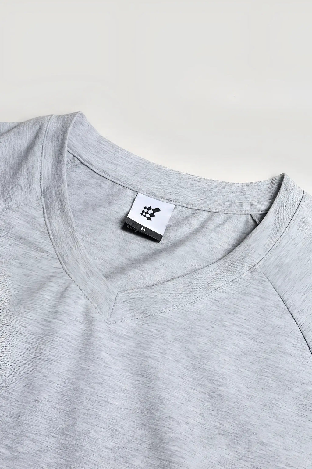 A heather gray v neck muscle-fit t-shirt with subtle textured fabric and a small white brand tag at the collar